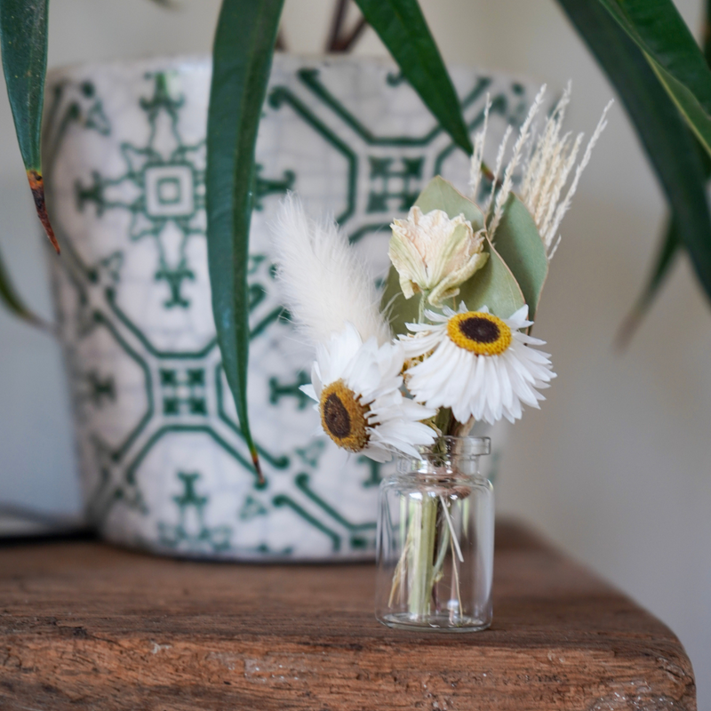A white dried flower mini bouquet in a mini vase