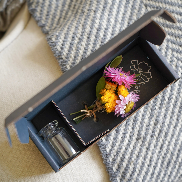 A pink and yellow dried flower mini bouquet in a box