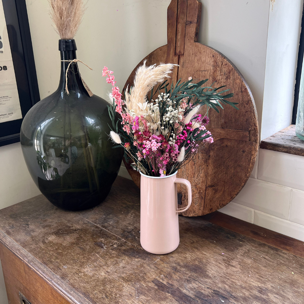 A pink dried flower bouquet in a pink vase