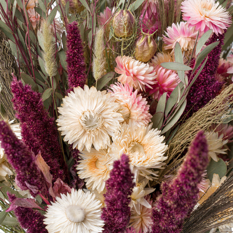 A close up of a pink and cream dried flower bouquet