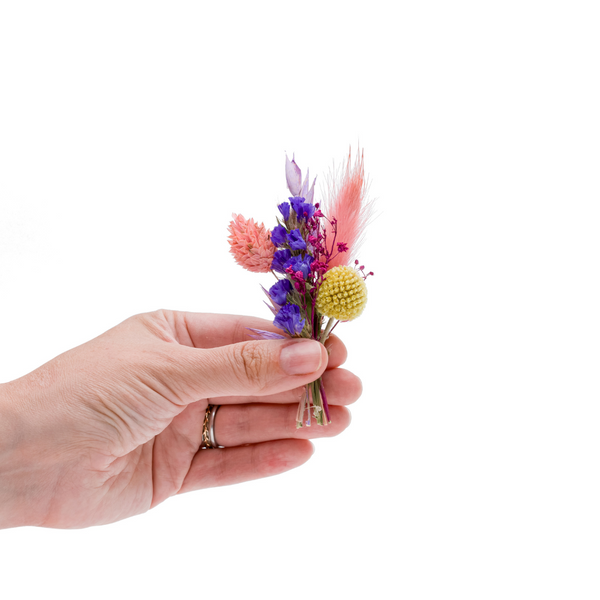 A bright colourful dried flower mini bouquet in a hand