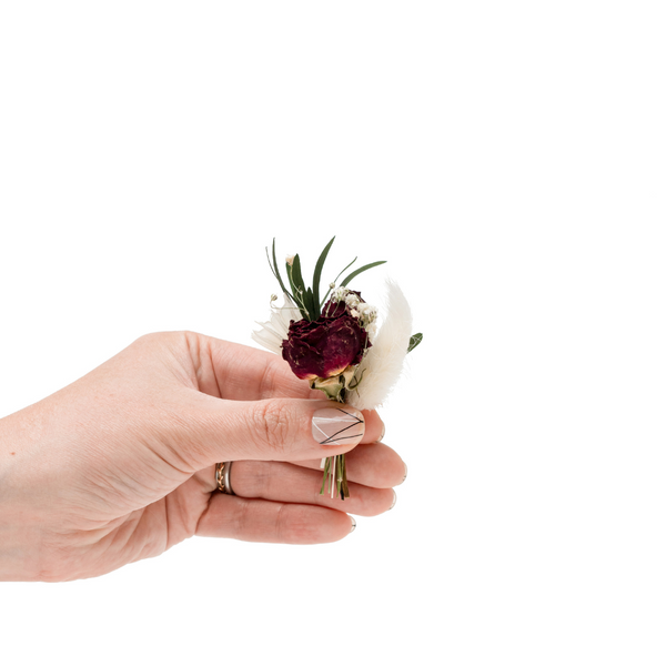 A red and white dried flower mini bouquet in a hand