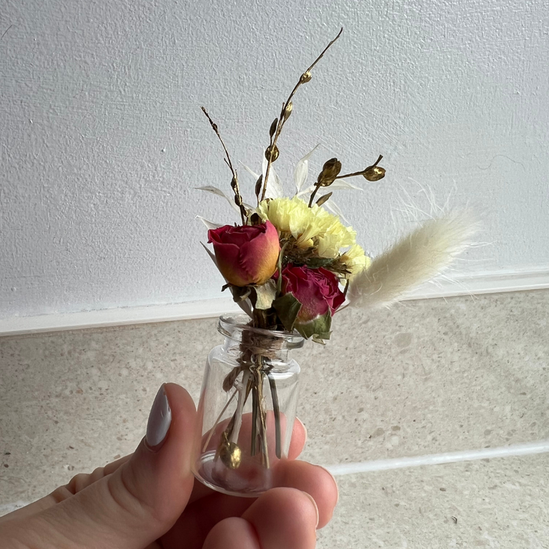 A red, yellow and gold mini bouquet in a mini vase