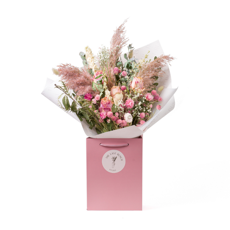 A pink dried flower bouquet in a bag