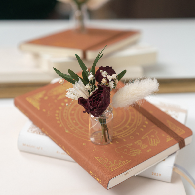 A red and white dried flower mini bouquet in a mini vase