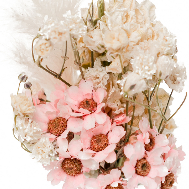 A close up of a pink and cream dried flower mini bouquet