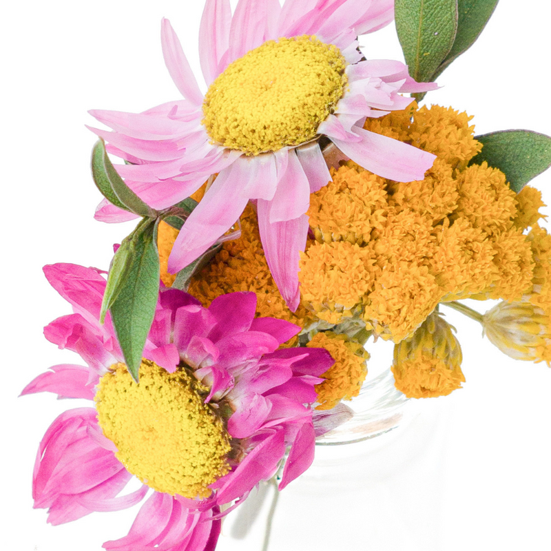 A close up of a pink and yellow dried flower mini bouquet