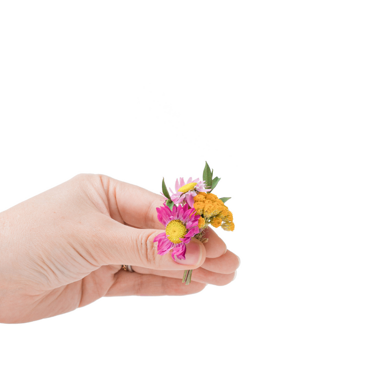 A pink and yellow dried flower mini bouquet in a hand