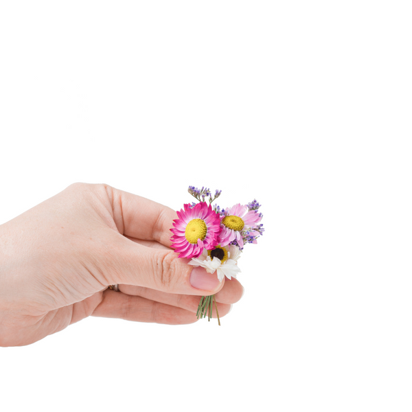 A pink and white dried flower mini bouquet in a hand