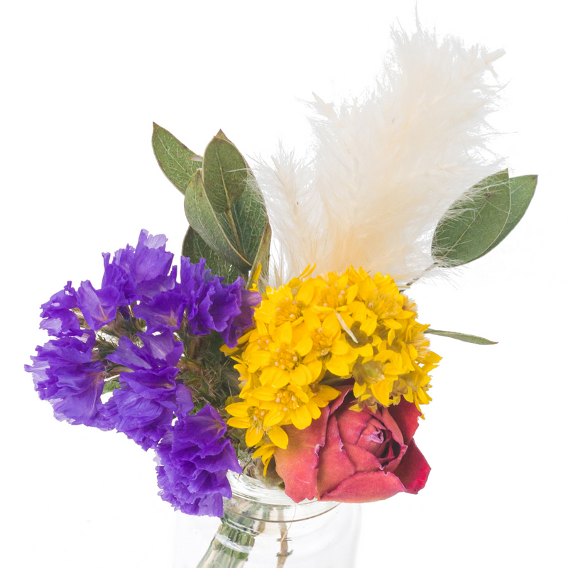 A close up of a colourful dried flower mini bouquet in a mini vase