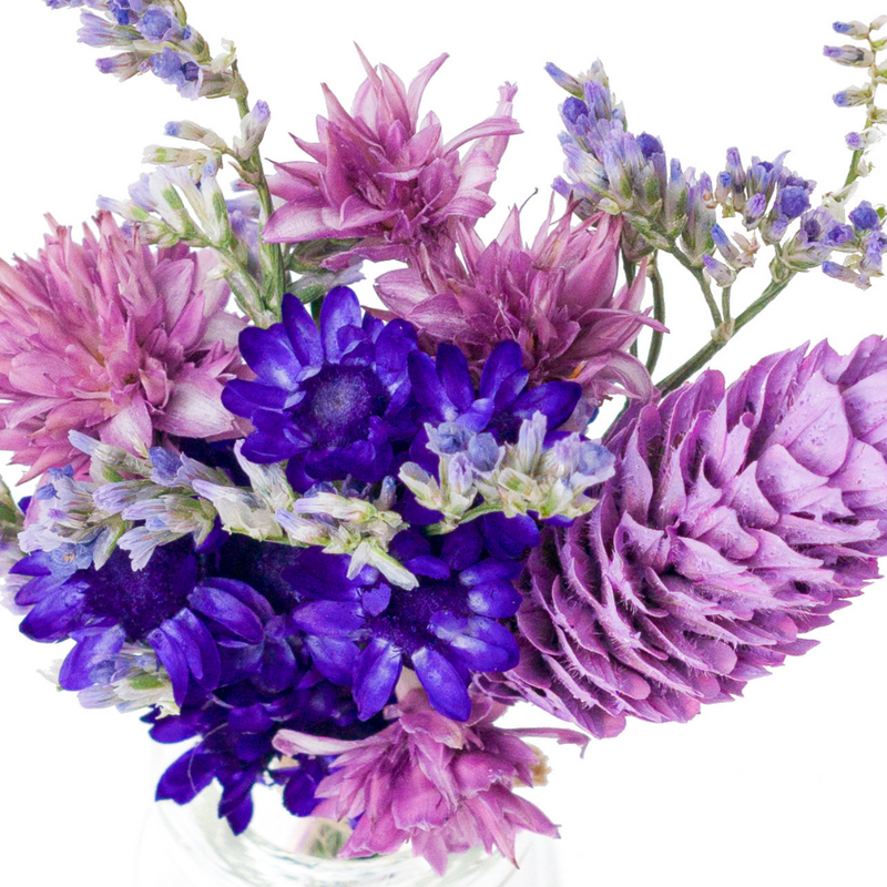 A close up of a purple dried flower mini bouquet in a mini vase