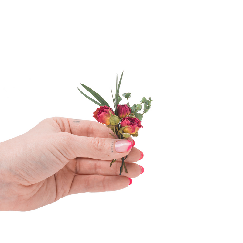 A mini bouquet made from dried red roses in a hand