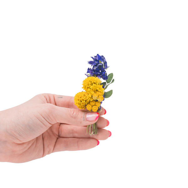 A blue and yellow dried flower mini bouquet in a hand