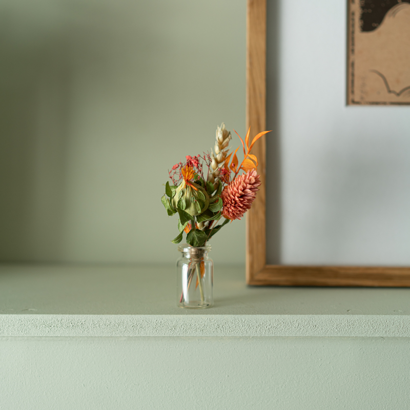 A orange dried flower mini bouquet in a mini vase
