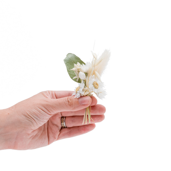 A white dried flower mini bouquet in a hand
