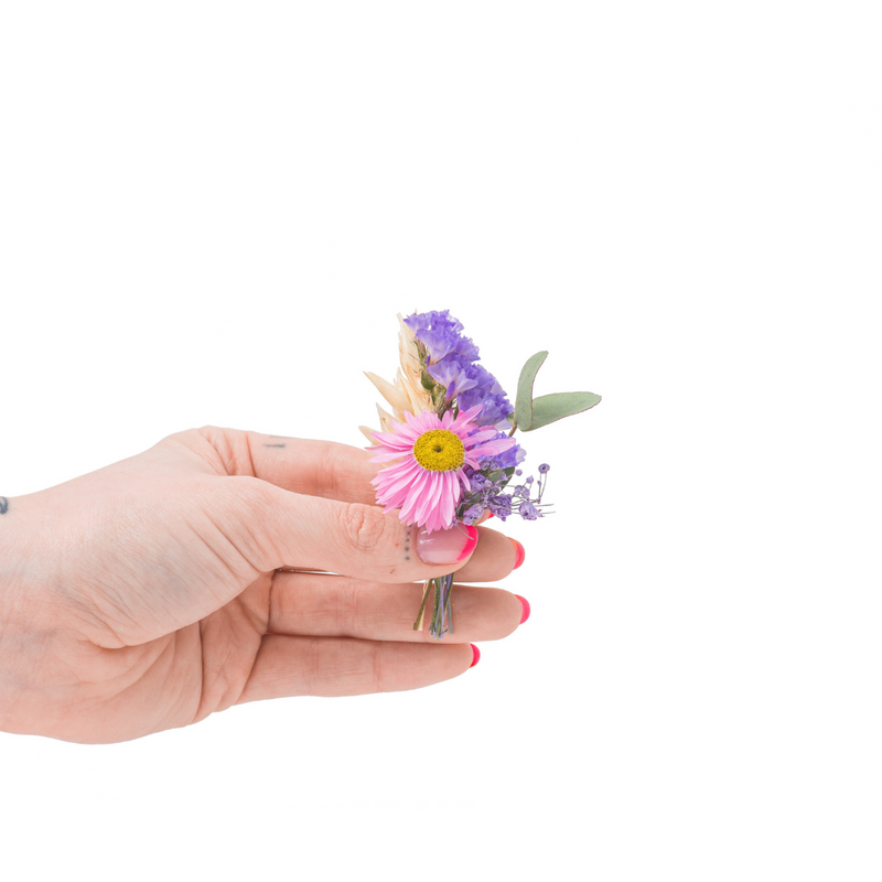 A pink and purple dried flower mini bouquet in a hand