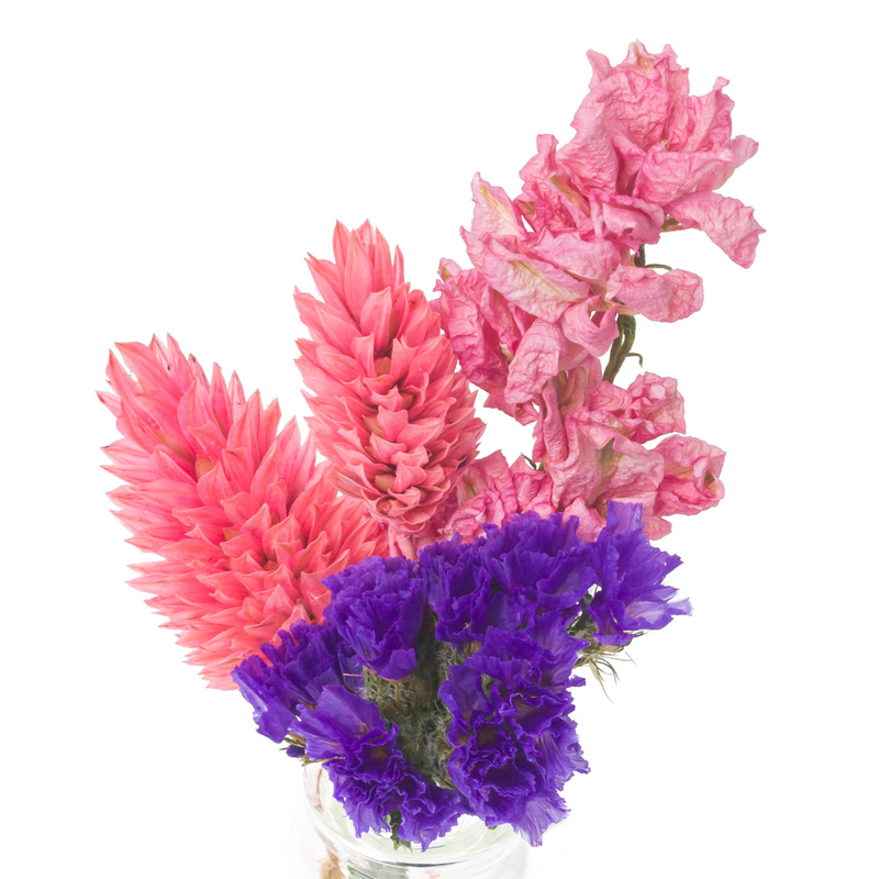A close up of a pink and purple dried flower mini bouquet in a mini vase